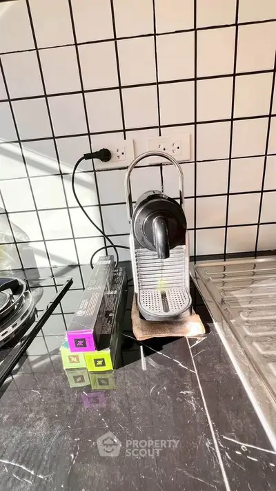 Modern kitchen corner with espresso machine and sleek black countertop.