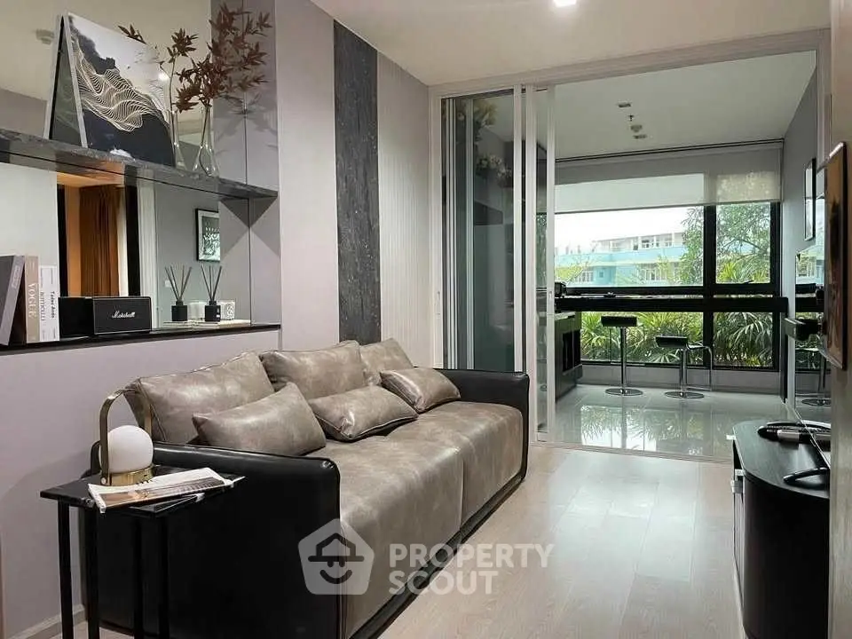 Modern living room with sleek decor and large windows overlooking greenery.