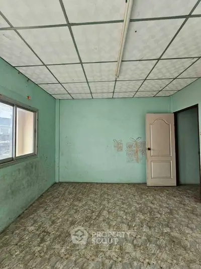 Spacious empty room with tiled floor and window, ideal for customization.