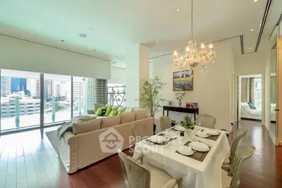 Luxurious open-plan living and dining area with elegant chandelier and city view.