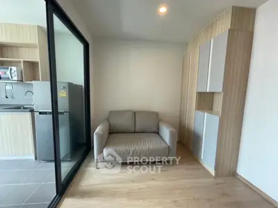 Modern living room with cozy sofa and sleek kitchen area in open layout apartment.