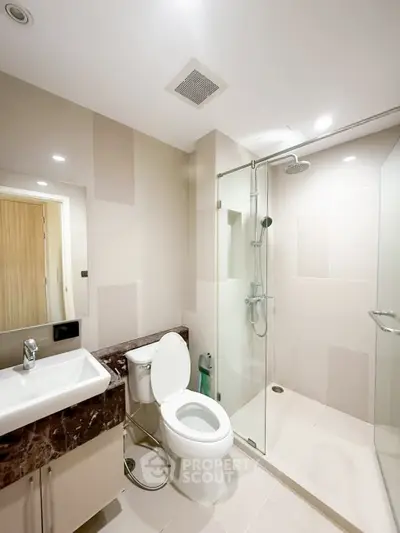 Modern bathroom with glass shower and sleek fixtures in a contemporary apartment.