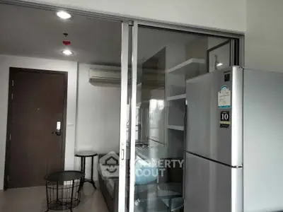 Modern apartment interior with sliding glass doors and stainless steel refrigerator.