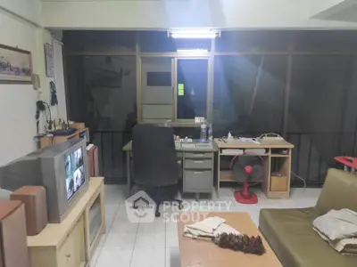 Cozy living room with vintage TV and desk setup, ideal for work and relaxation.