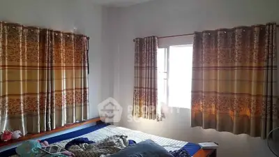 Cozy bedroom with natural light and patterned curtains, perfect for relaxation.