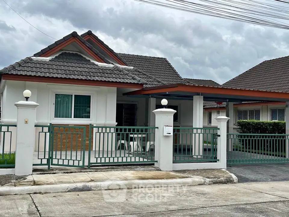 Charming single-story house with tiled roof and gated entrance in a serene neighborhood.