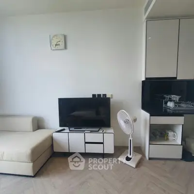 Modern living room with sleek furniture and minimalist design, featuring a TV and fan for comfort.