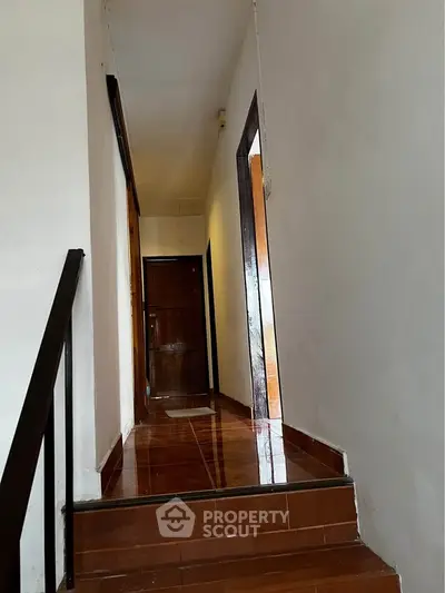 Charming hallway with polished wooden floors and white walls leading to a cozy interior space.