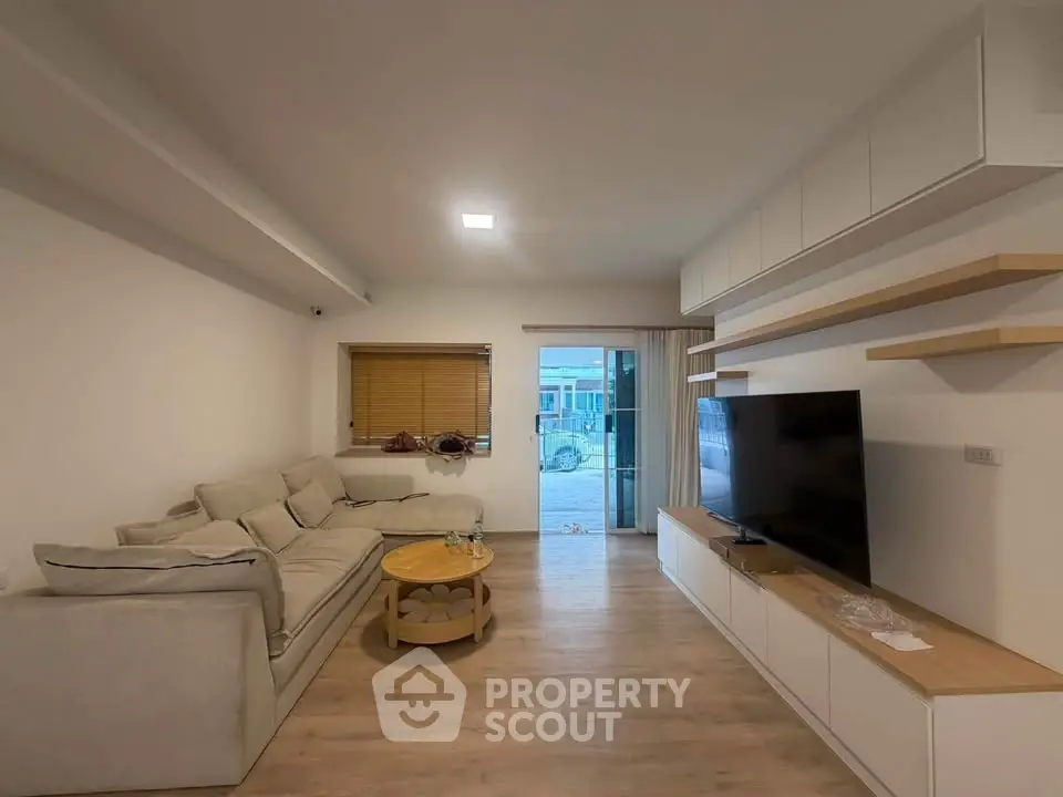 Spacious modern living room with cozy sofa and large TV, perfect for relaxation.