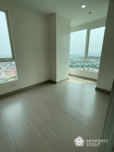 Spacious empty room with large windows offering stunning city views in a modern apartment.