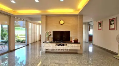 Spacious living room with modern decor and garden view, featuring sleek flooring and ambient lighting.