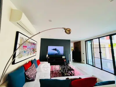 Spacious modern living room with stylish decor and large glass doors opening to a balcony.