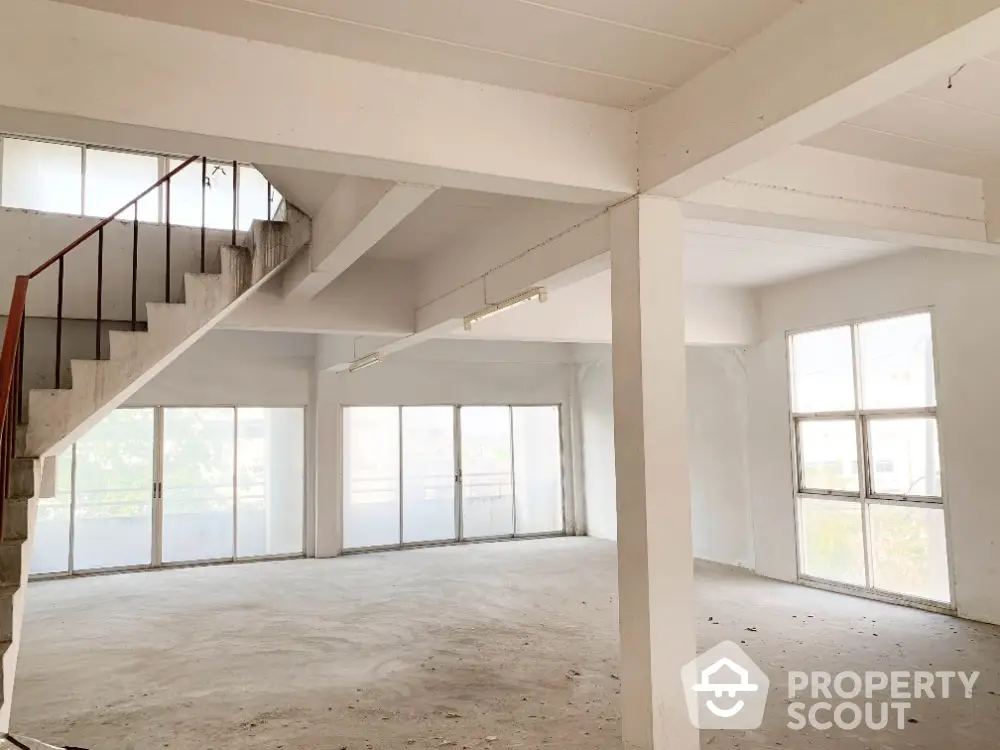 Spacious two-level living space with abundant natural light, featuring large windows and a modern staircase, ideal for a luxurious open-plan design.