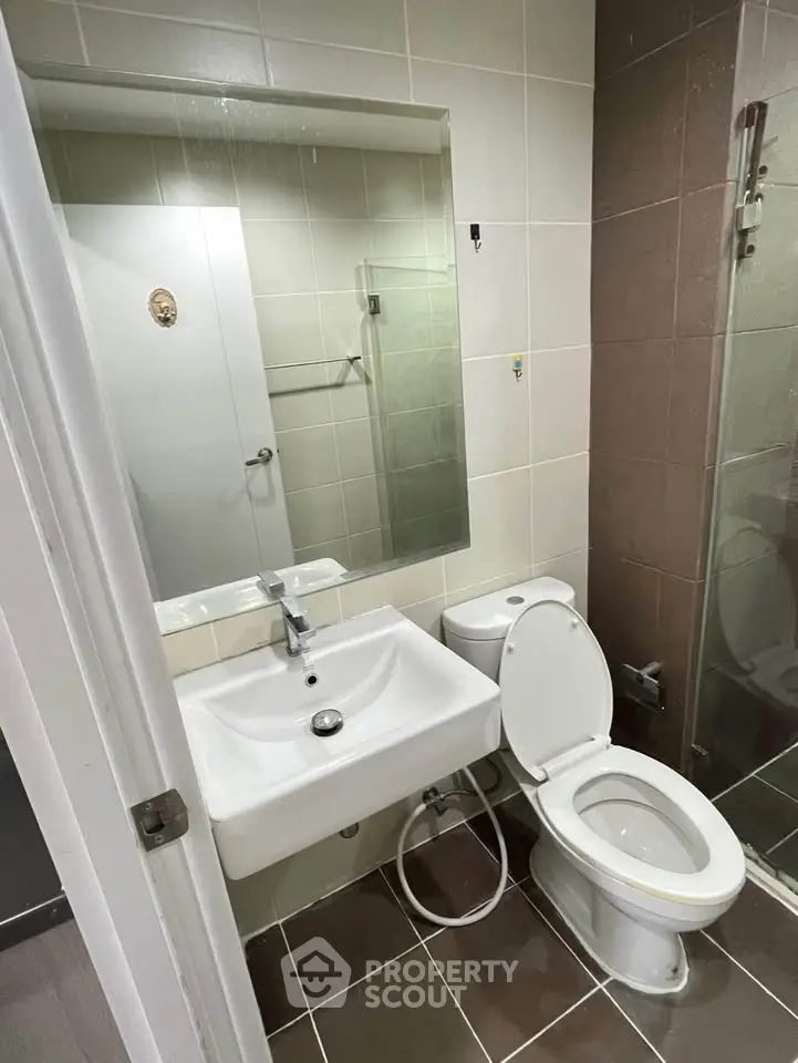 Modern bathroom with sleek fixtures and glass shower enclosure in a contemporary apartment.