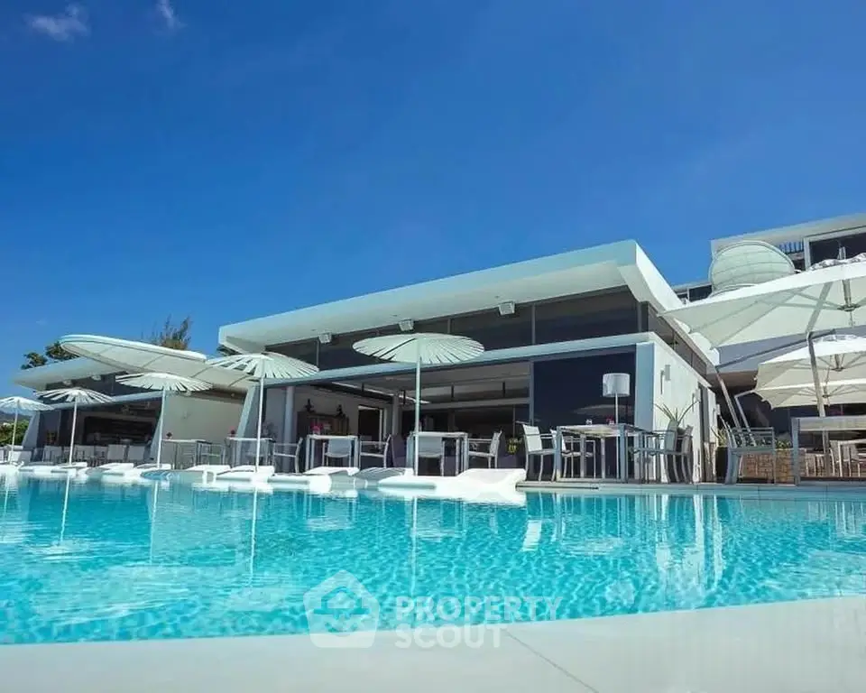 Luxurious modern building with stunning poolside view and elegant outdoor seating.