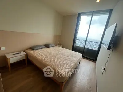 Modern bedroom with large window and city view, featuring a comfortable bed and sleek design.