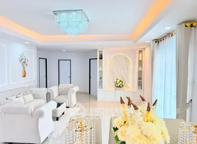 Luxurious living room with elegant chandelier and plush white sofas in a modern home.