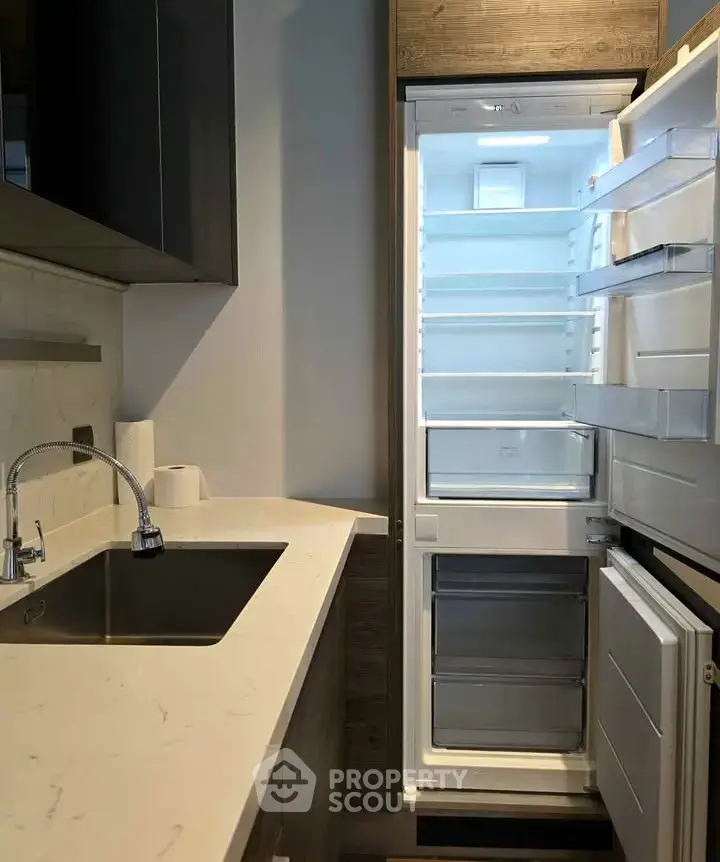 Modern kitchen with sleek design featuring built-in fridge and stylish sink area.