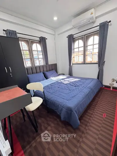 Cozy bedroom with modern furnishings and large windows offering natural light.