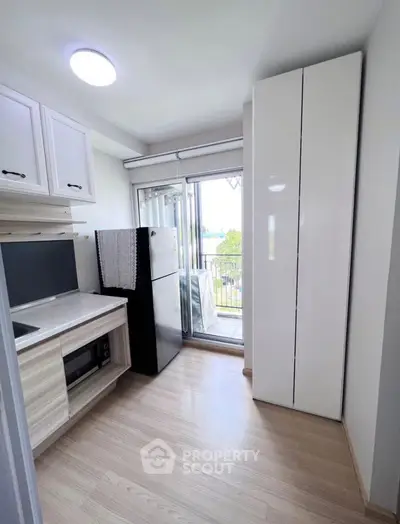 Modern kitchen with sleek cabinetry and balcony access in a compact apartment.