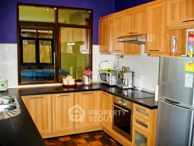 Modern kitchen with wooden cabinets, stainless steel appliances, and vibrant purple walls.