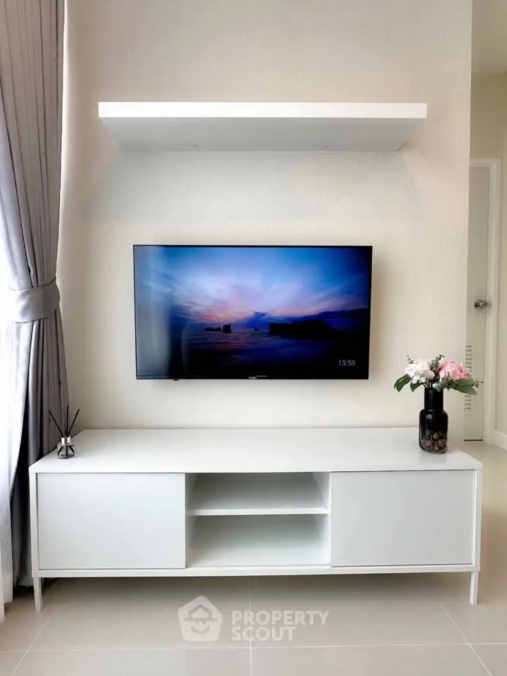 Modern living room with sleek white TV stand and wall-mounted flat screen, accented by elegant decor.