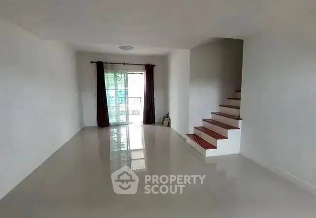 Spacious empty living room with glossy floors and staircase leading to upper level.