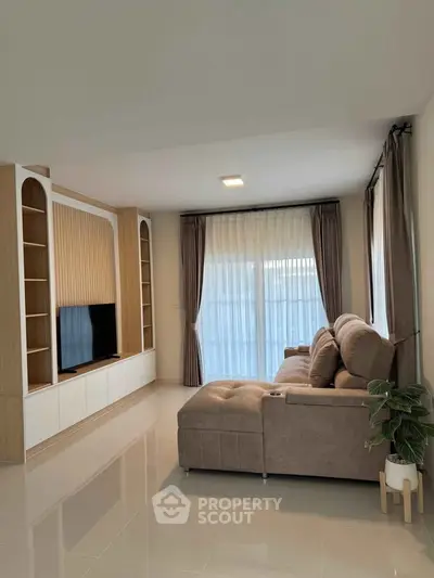 Spacious living room with modern sofa and built-in TV unit, perfect for relaxation.