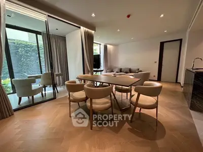Modern open-plan living and dining area with elegant furnishings and garden view.