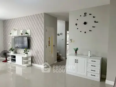 Modern living room with stylish decor and wall-mounted TV, featuring sleek white furniture and unique wall clock.