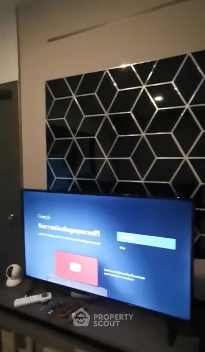 Modern living room with geometric wall design and smart TV setup.