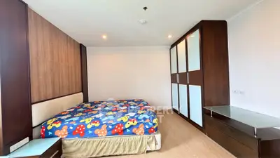 Spacious bedroom with modern wooden furniture and colorful bedding in a stylish apartment.