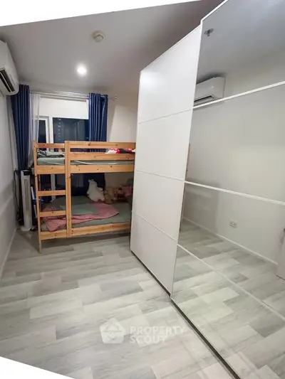 Cozy bedroom with bunk bed and mirrored wardrobe, perfect for maximizing space in modern living.