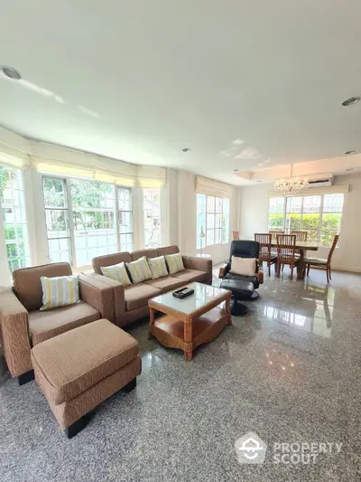 Spacious living room with large windows and elegant furniture, perfect for family gatherings.