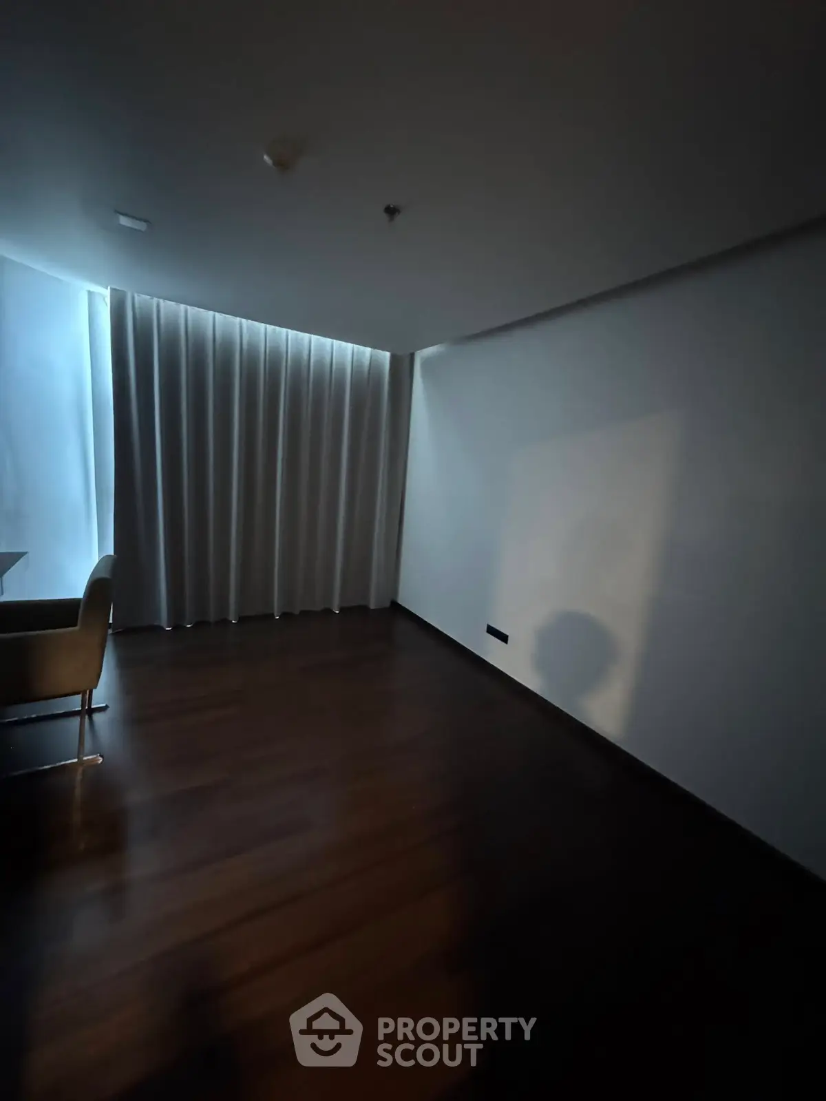 Minimalist room with dark wood flooring and soft lighting