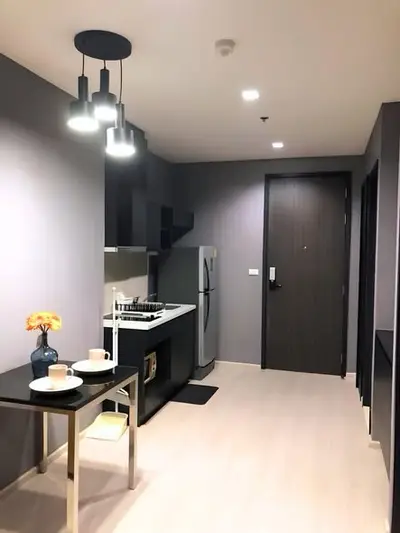 Modern kitchen with sleek design, featuring a fridge, stove, and dining area in a stylish apartment.