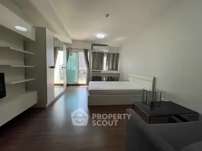 Spacious modern bedroom with balcony and city view, featuring sleek furniture and ample natural light.