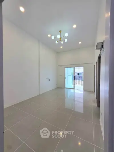 Spacious modern living room with high ceiling and elegant lighting, featuring large windows for natural light.