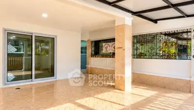 Spacious covered patio with tiled flooring and sliding glass doors, perfect for outdoor relaxation.