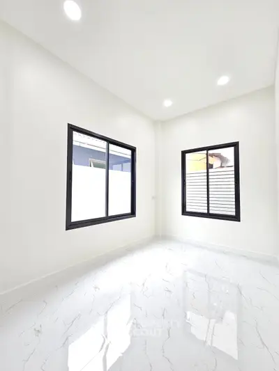 Bright and modern empty room with large windows and glossy white tile flooring.