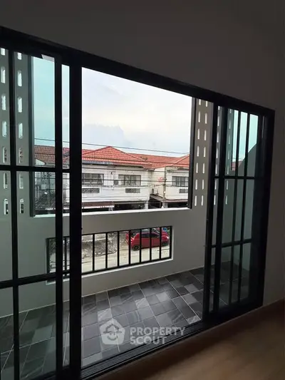 Spacious balcony with sliding glass doors offering a view of charming red-roofed houses.
