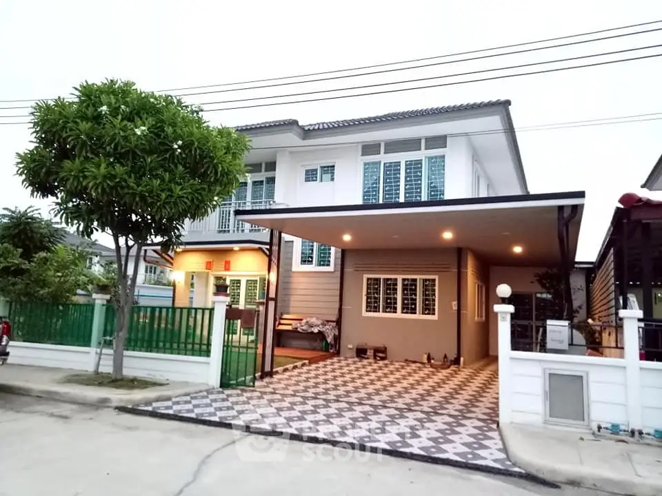 Charming two-story house with spacious driveway and lush greenery in a serene neighborhood.