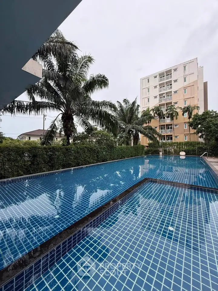 Luxurious outdoor pool with palm trees and modern building backdrop, perfect for relaxation and leisure.