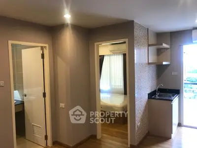 Modern apartment interior with open kitchen and bedroom view, featuring sleek design and natural light.