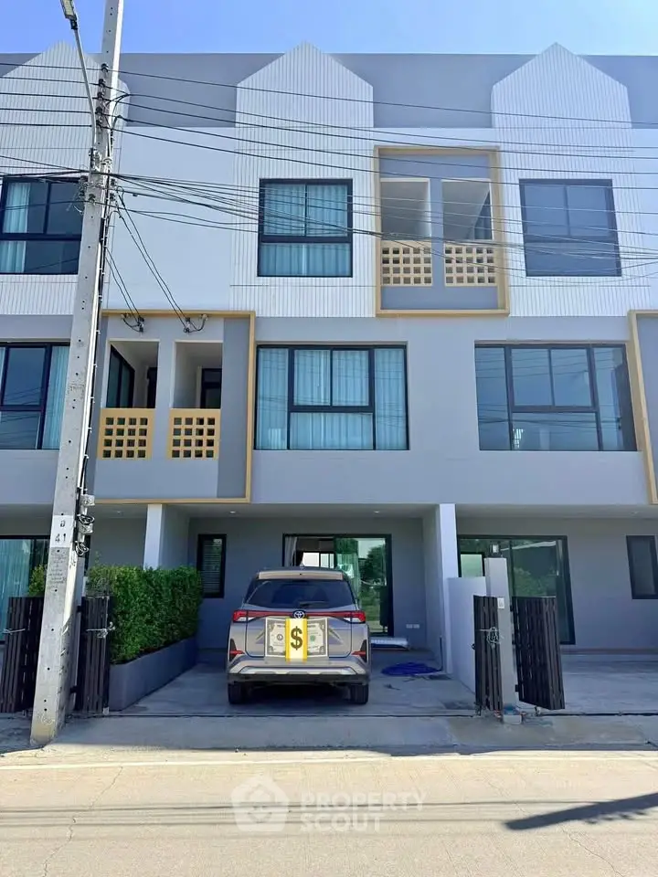 Modern townhouse with three floors and a car parked in the driveway, showcasing contemporary design.