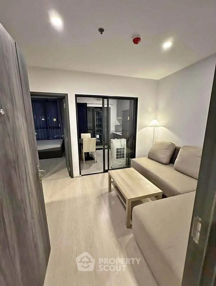Modern living room with cozy sofa and sliding glass doors leading to bedroom.
