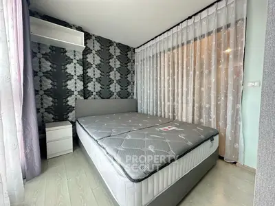 Modern bedroom with stylish wallpaper and large window draped with sheer curtains.