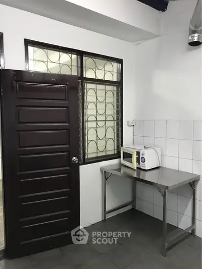 Compact kitchen corner with microwave and tiled walls, ideal for small apartments.