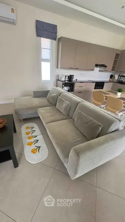 Modern open-plan living room with sleek kitchen and cozy gray sofa.