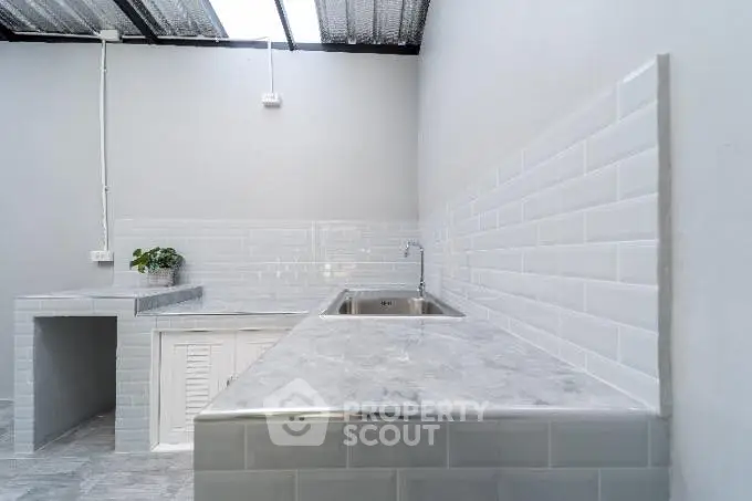 Modern minimalist kitchen with sleek marble countertops and white subway tile backsplash.